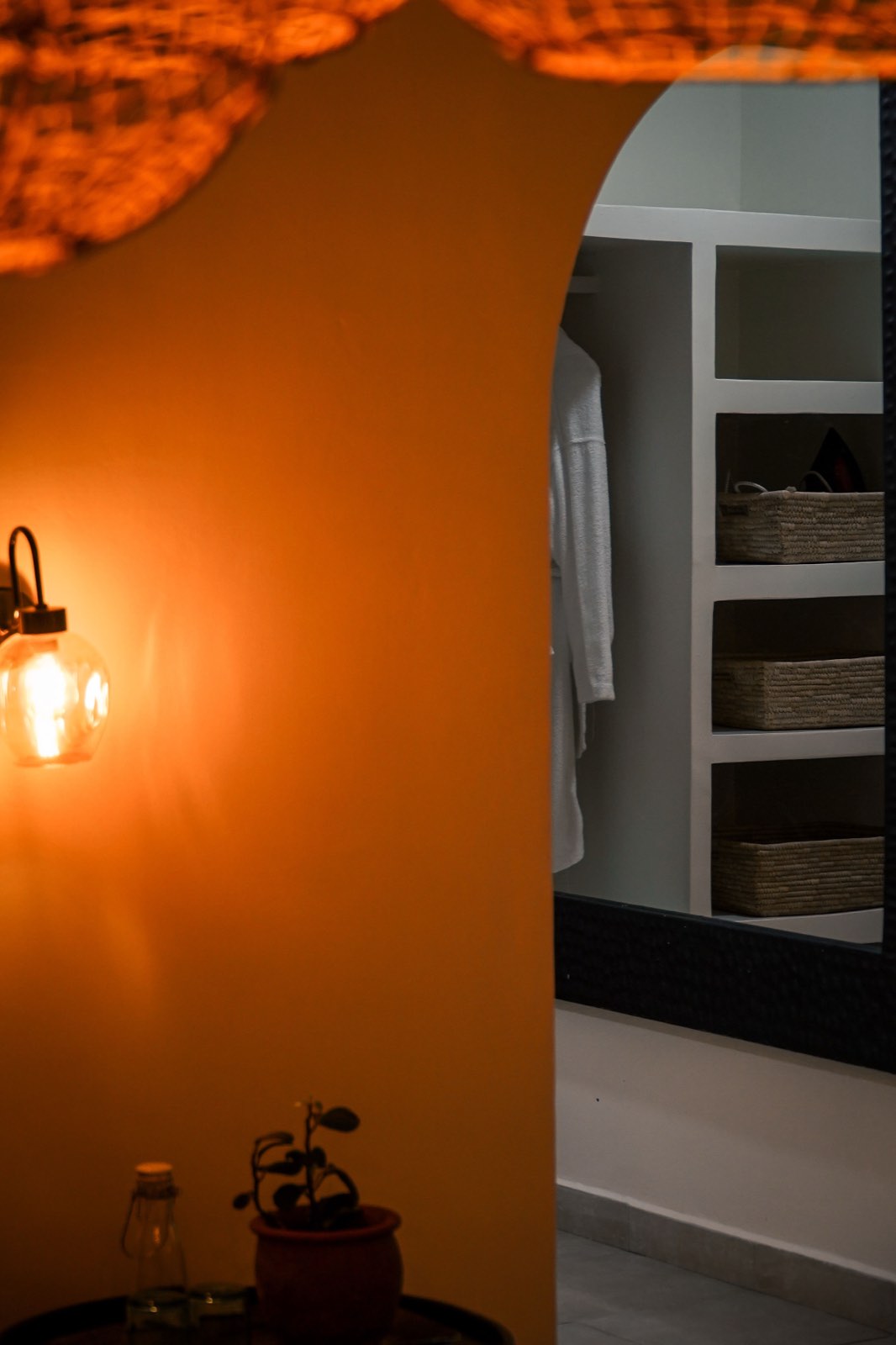Wardrobe and robes beside a lit wall sconce