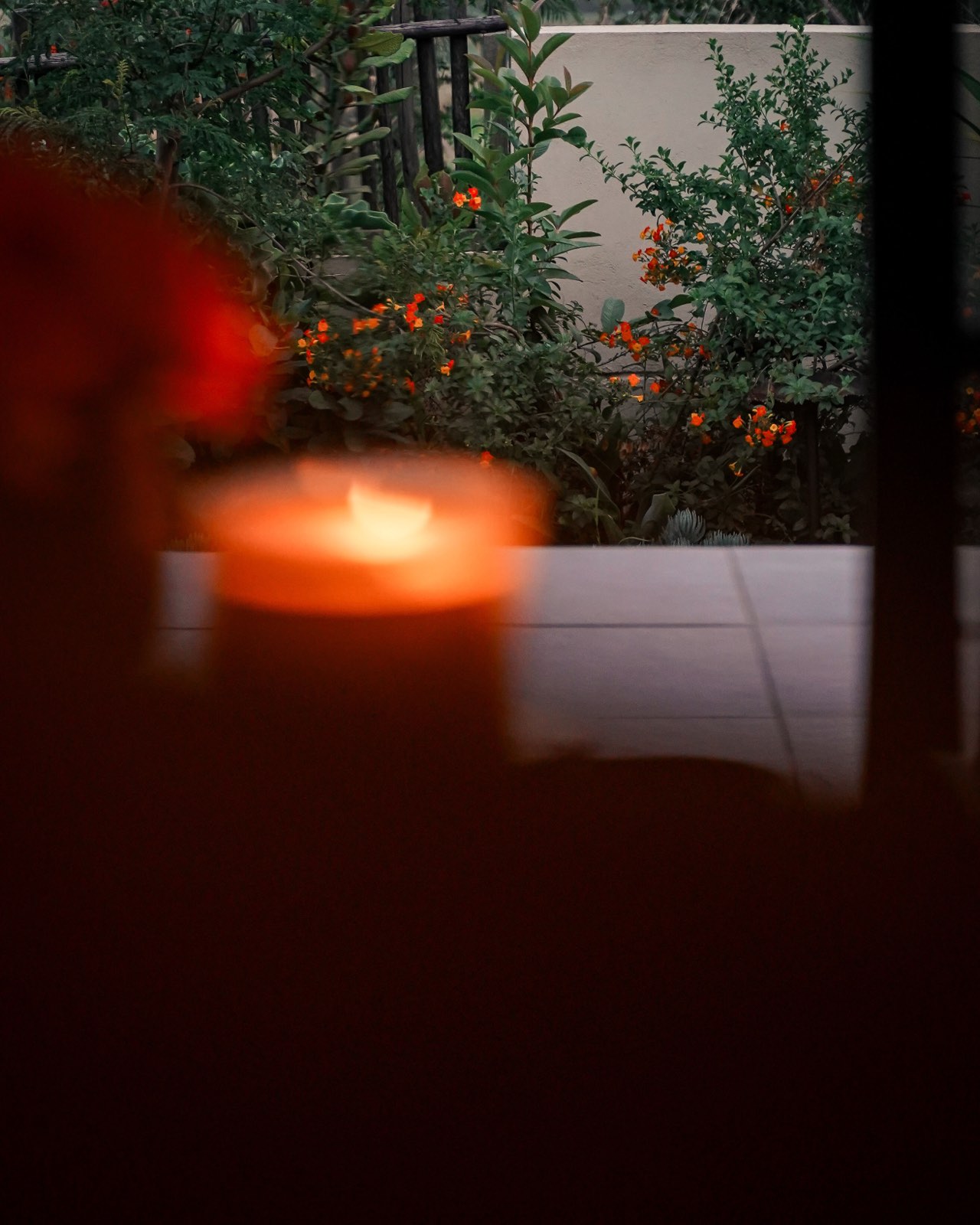 A Hatua candle burning at dusk beside the garden